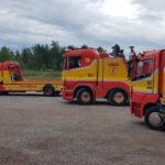 Tre Assistancekåren bilar står uppställda på grusplan.